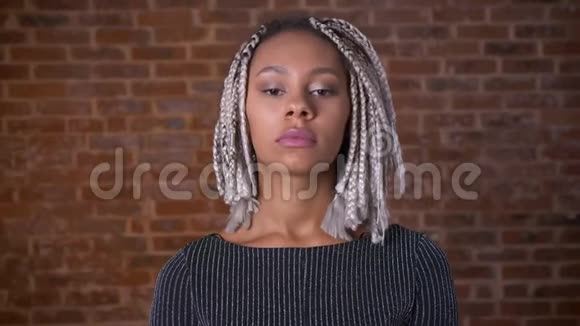 年轻的非洲严肃女孩与可怕的女孩看着相机闭上眼睛砖墙的背景视频的预览图