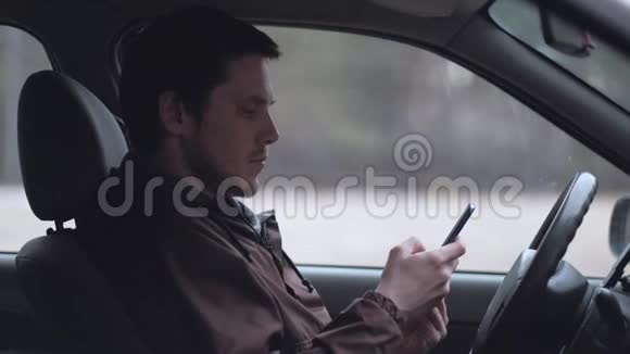 一个年轻人使用智能手机坐在汽车的船舱里视频的预览图