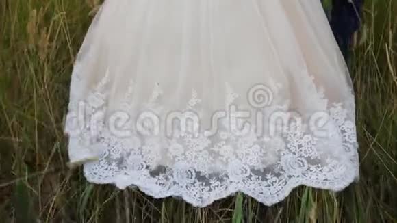 新娘穿着白裙子穿过田野长裙滑过草地特写镜头慢动作美丽的新娘视频的预览图