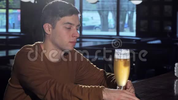 从杯子里喝下美味的啤酒后年轻人对着镜头微笑视频的预览图