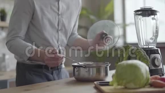 英俊好看的男人穿着衬衫在厨房煮汤理念健康食品居家烹饪那个家伙视频的预览图