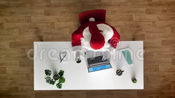 圣诞老人在办公室工作手提电脑打字喝酒空中观景上下拍摄视频的预览图