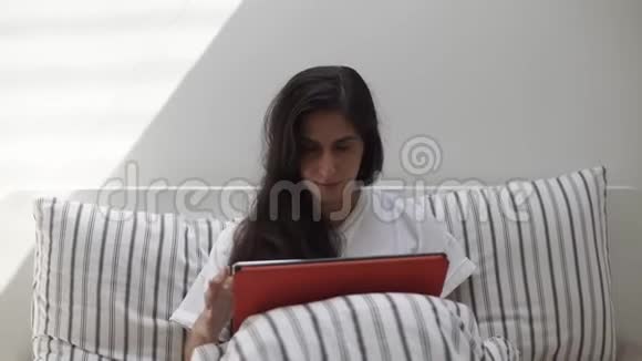 一个女人在床上用平板电脑的正面镜头视频的预览图