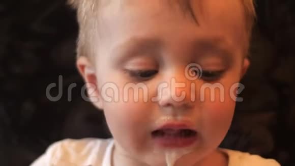 一个小男孩在华夫饼杯里舔白色香草冰淇淋的肖像用冰淇淋和视频的预览图