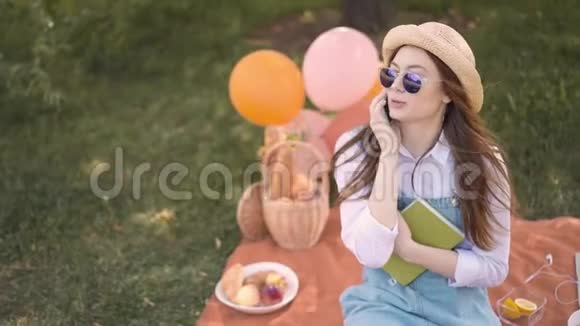 公园里戴着草帽和太阳镜的开朗的姜科大学生打电话视频的预览图
