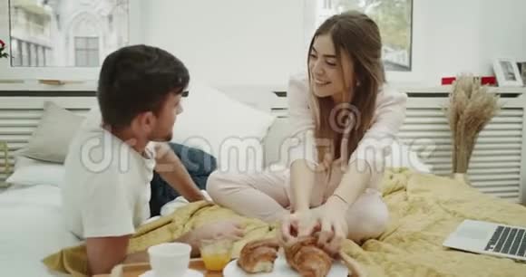 一对夫妇在床上一起吃法国早餐一起吃羊角面包视频的预览图