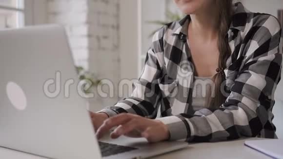 女企业主博主正在使用笔记本电脑在家里的工作场所打字视频的预览图