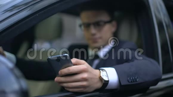 严肃的商人在汽车等候时通过电话测试新的商务应用程序视频的预览图