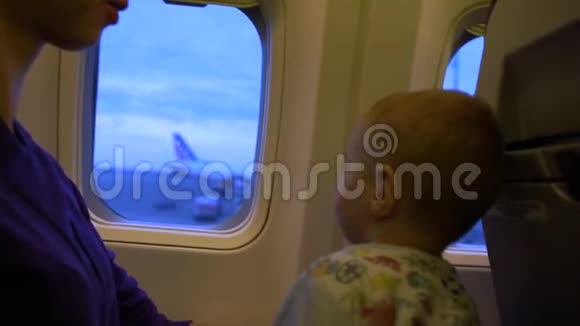 妈妈和宝宝缓慢地看着窗外的飞机视频的预览图