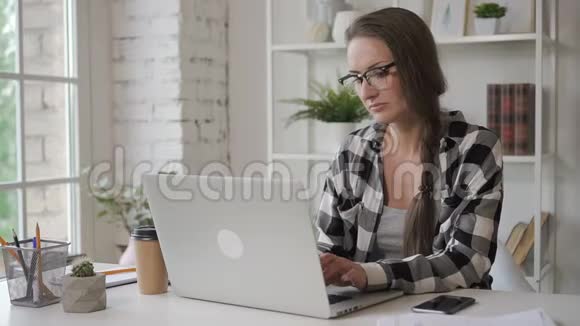 女作家正在打字喝着咖啡坐在桌上拿着投资笔记本电脑视频的预览图