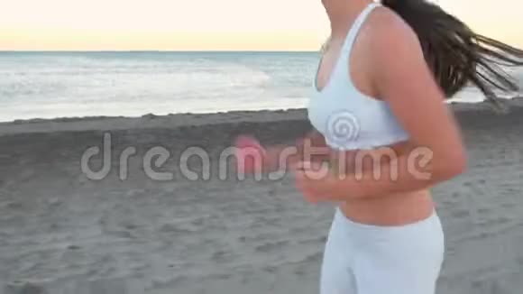 秋日日出时年轻女子正在海边的沙滩上慢跑特写双腿侧景视频的预览图