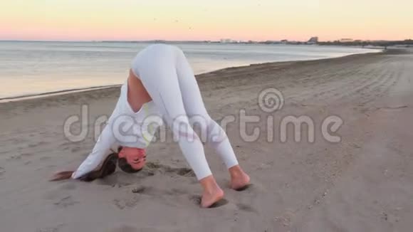 秋日日出时年轻女子正在沙滩上做瑜伽视频的预览图