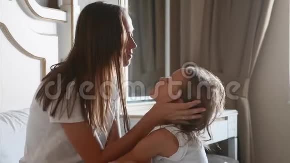 年轻的母亲在家里的卧室里爱抚她的小女儿视频的预览图