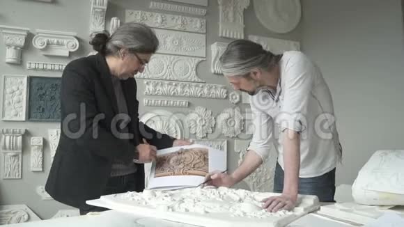 两个成熟的男性雕塑家把造型比作桌子手里拿着视频的预览图