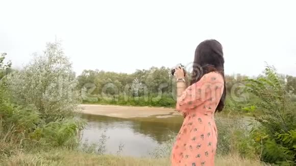一个头发长长的黑发女孩在河里拍照慢动作美丽的风景视频的预览图