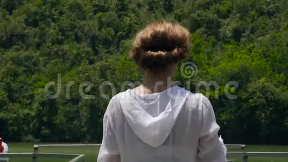 年轻女子在河桥和青山背景上抽烟在湖岸和山上抽烟的女孩视频的预览图