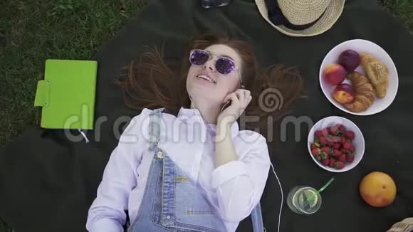 戴着墨镜穿着工作服躺在草地上听音乐的姜姑娘视频的预览图