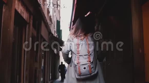 镜头跟随时尚女商人背着背包走在黑暗的古老街道在威尼斯意大利慢动作视频的预览图