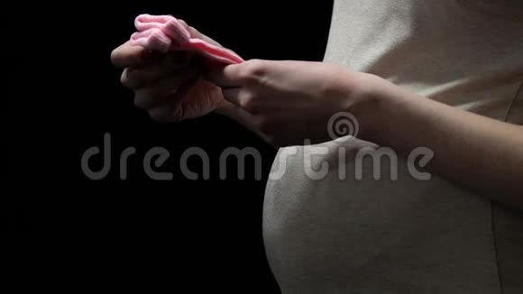 一位孕妇把粉红色的袜子隔离在黑色上担心宝宝的健康视频的预览图
