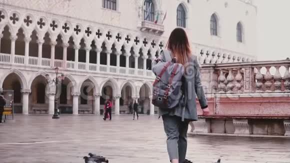 意大利威尼斯圣马可市广场上的一群鸽子跟随着快乐的女游客慢动作视频的预览图