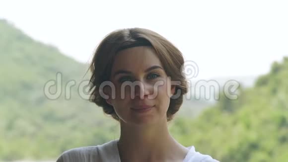 描绘夏日的年轻女子青山景观在覆盖着绿色的山上看镜头的脸女孩视频的预览图