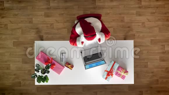 圣诞老人在办公室工作手提电脑听耳机音乐打字鸟瞰上下拍摄写文字视频的预览图