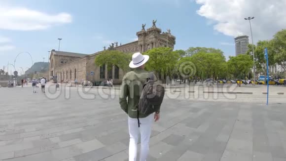 一个年轻人带着背包和帽子在西班牙巴塞罗那市中心散步视频的预览图