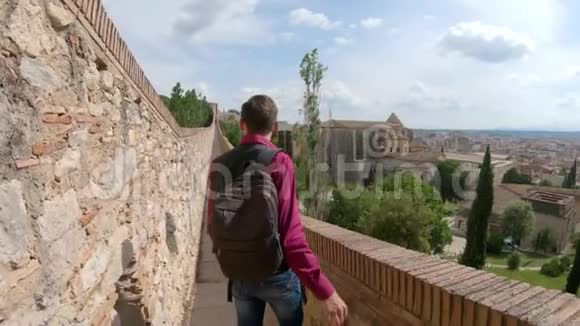 一个带背包的年轻人一个游客沿着西班牙吉罗纳的堡垒墙走GI的堡垒墙视频的预览图