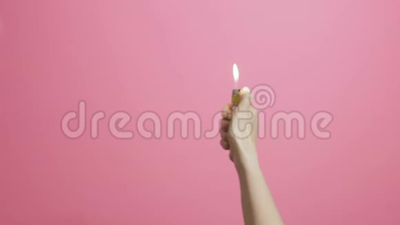 女人的手打开打火机在粉红的彩色画室背景上闪烁扇子的轻创意的想法开始了视频的预览图