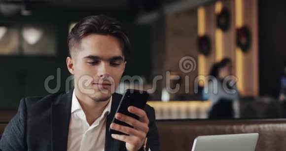 帅哥使用智能手机坐在咖啡馆或同事办公室喝茶成功商人的肖像视频的预览图