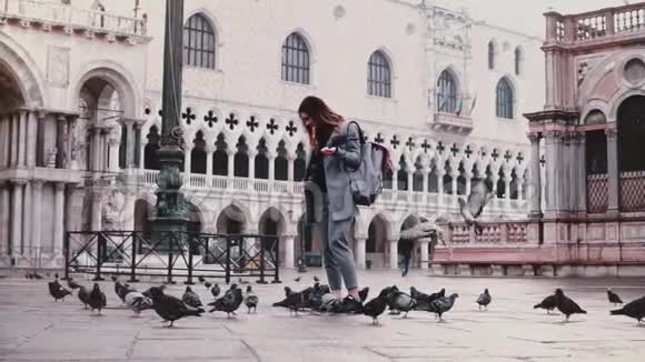 快乐迷人的欧洲旅游妇女鸽子坐在她的手臂上微笑着站在圣马可威尼斯慢动作视频的预览图