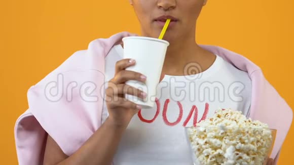 兴奋的女孩从纸杯喝饮料拿着爆米花碗电影院视频的预览图