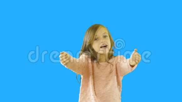 一个有着卷发的小女孩看着镜头微笑着挥舞着手臂于是她自言自语微笑着视频的预览图