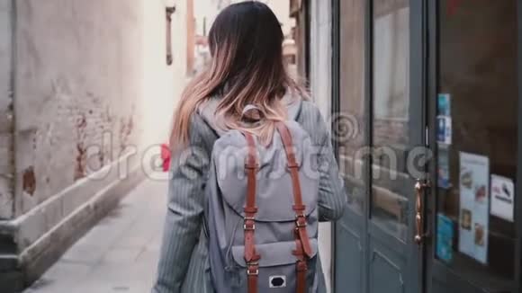 镜头跟随时尚的女游客背包和长发沿着旧的夏季街道在威尼斯慢动作视频的预览图