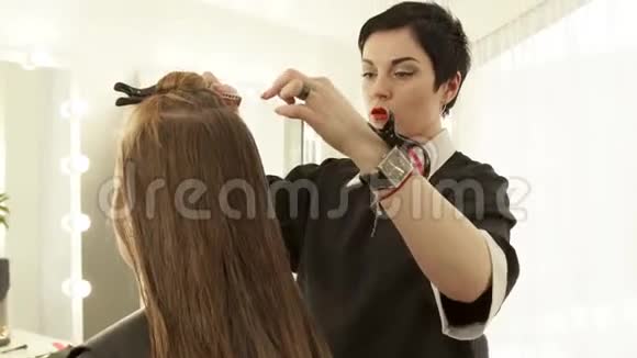 美容院女理发师为女理发镜梳长发把剪发的头发收起来视频的预览图