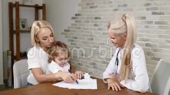 家庭诊所漂亮的母亲和她在医生办公室的女孩子孩子画画妈妈和医生说话一般视频的预览图