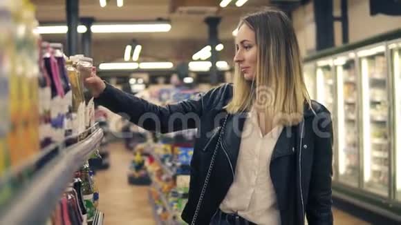 超市里微笑女人的侧视选择果汁装在瓶子里然后放在篮子里金发微笑的女人视频的预览图
