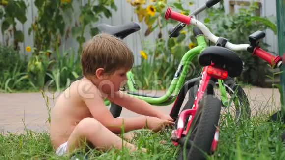 修理自行车的男孩前后院背景交通和儿童在草地上循环快乐童年概念视频的预览图