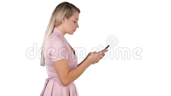 穿着粉色连衣裙的漂亮女人在白色背景上用智能手机发短信视频的预览图