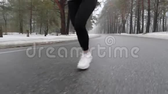年轻迷人的白种人女孩在冬天的雪地公园里奔跑特写双腿前跟射击慢动作视频的预览图