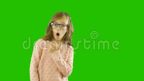 戴眼镜的有趣的金发小女孩戏谑地欣赏用手指展示的东西展示她的惊喜视频的预览图