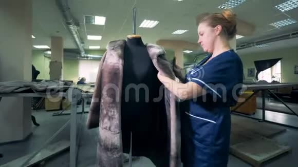 裁缝正在刷一件挂在人体模型上的毛皮大衣视频的预览图