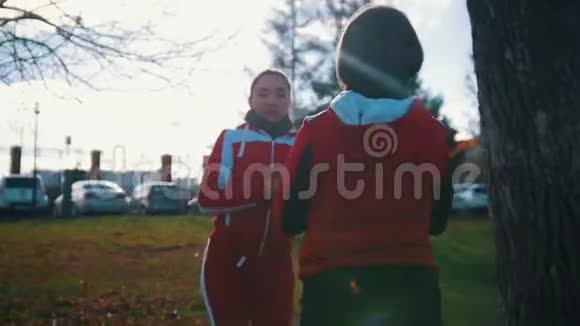 两个穿着运动服装的年轻女子在公园里互相蹲着视频的预览图
