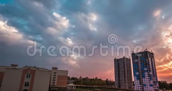 在多层公寓楼的背景下傍晚蓬松的卷曲翻滚的夕阳云视频的预览图