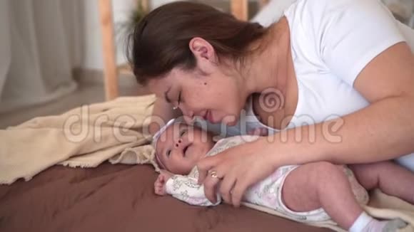 一个家庭在床上微笑妈妈在那里看触摸和交谈她的小女儿视频的预览图