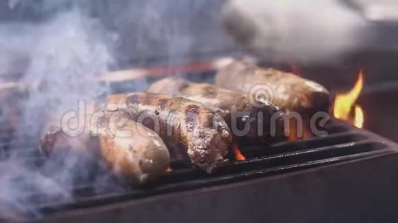 辣猪肉香肠是在热烤架上炸的火和烟他们用钳子翻过来烹饪过程慢动作视频的预览图