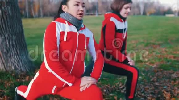 两个穿着运动服装的年轻女子在公园里近距离地做腿上的跳跃视频的预览图