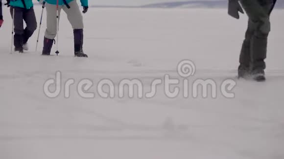 在寒冷的冬天徒步旅行者靠在树枝上走在白色的雪地上腿上有特写镜头视频的预览图