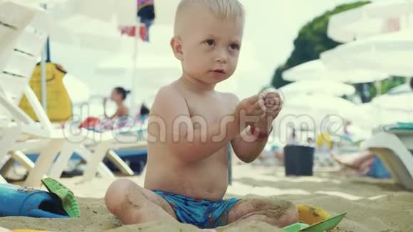那个可爱的小男孩在海边玩沙子玩具孩子们在暑假在海滩度假视频的预览图
