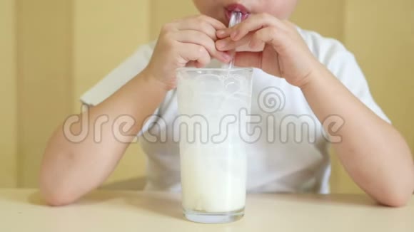 慢动作幼儿通过吸管从杯子里喝牛奶把泡泡吹成玻璃杯视频的预览图